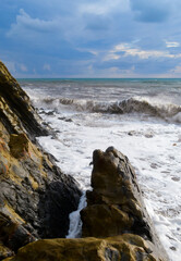 Storm at sea, waves crash on rocks.