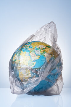 The concept of protecting the world from plastic waste, fighting environmental pollution, fighting for the environment, a globe in a black garbage bag on a light background.