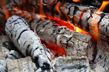 Glowing embers in hot red color, abstract background. The hot embers of burning wood log fire. Firewood burning on grill. Texture fire bonfire embers.