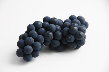 Black grapes, large fresh fruits with green leaves on a white background