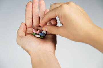Woman taking a pill.Colorful pills in woman's handful on white background.