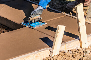 Construction Worker Using Hand Groover On Wet Cement Forming Coping Around New Pool