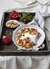 Bowl of greek yogurt with granola , fresh fig and pomegranate seeds- 