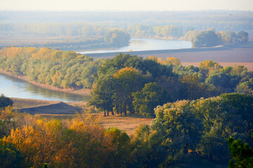 Naklejka premium bright colorful autumn forest landscape, trees near river and blue sky, view from high hill
