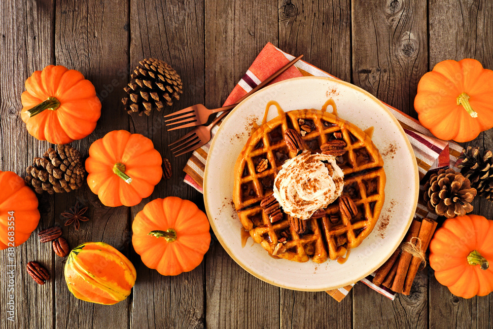 Poster pumpkin spice waffle with whipped topping, caramel and pecans. overhead view table scene on a dark w