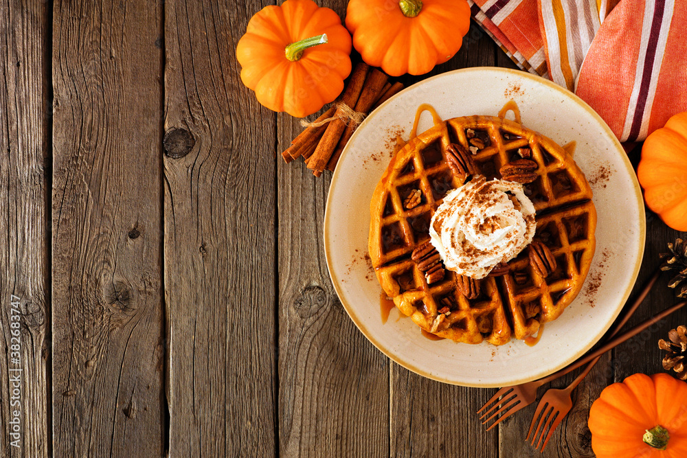 Poster pumpkin spice waffle with whipped topping, caramel and pecans. above view table scene on a dark wood