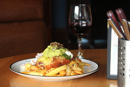 Chicken Parmigiana Pub Lunch On A Table With A Glass Of Red Wine And Seating In Background. The Meal Is Mexican Chicken Parmigiana With Chips And Coleslaw. Chicken Parma Or Parmi.