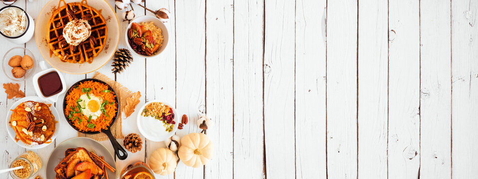 Fall breakfast or brunch buffet side border against a white wood banner background. Pumpkin spice pancakes, waffles, apple french toast, oatmeal, egg skillet, yogurt. Top view with copy space.