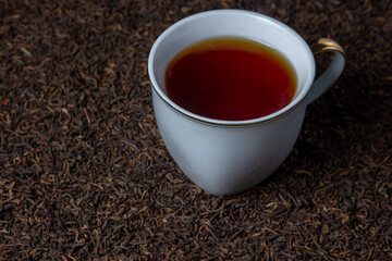 Leaf tea. a lot of loose tea. A cup of tea stands on loose tea