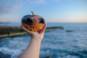 orange pumpkin head for Halloween in hand. a ghastly burnt fire head Jack