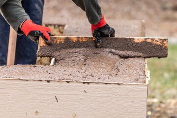 Construction Worker Leveling Wet Cement Into Wood Framing