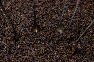 Leaf tea. a lot of loose tea. Teaspoons sticking out of a pile of loose tea