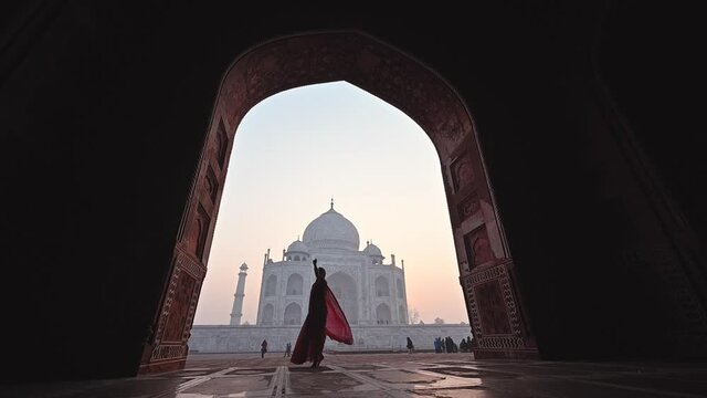 Asian woman in dressing red saree indian traditional dress dancing inTaj Mahal, Agra, India