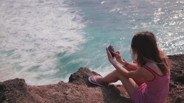 Woman tourist taking photos with her smartphone at a vacation on tropical island.