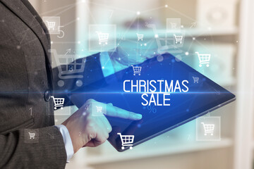 Young person makes a purchase through online shopping application with CHRISTMAS SALE inscription