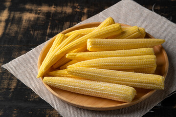 Fresh young baby corn on wooden plate background