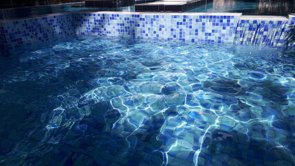 The pool is lined with a mosaic of blue and white colors. Sun glints play in the pool water.