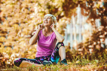 Senior woman exercising in park while listening to music.