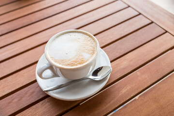 ceramic cup of coffee on table in coffee shop cafe.coffee cup latte art in cafe on wooden table.Classic Coffee Cup,Italian Cappuccino, Delicious Morning hot drink.