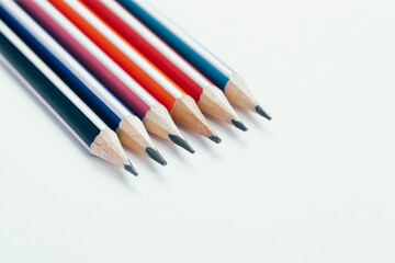Multicolored wooden graphite pencils on light background.