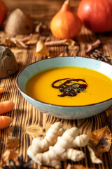 orange Suppe aus Kürbissen vom Hokkaido in einer Schale auf einem braunem Tisch aus Holz im Herbst zu Halloween