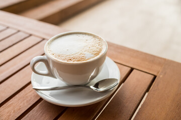 ceramic cup of coffee on table in coffee shop cafe.coffee cup latte art in cafe on wooden table.Classic Coffee Cup,Italian Cappuccino, Delicious Morning hot drink.