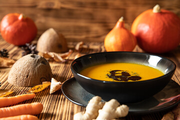 orange Suppe aus Kürbissen vom Hokkaido in einer Schale auf einem braunem Tisch aus Holz im Herbst...