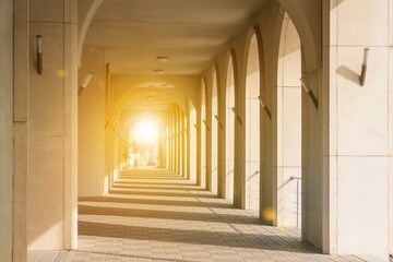Passage with columns in perspective to the glare of the sun. Lead to success in the light.