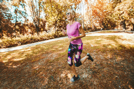 Elderly woman running with headphones in the park