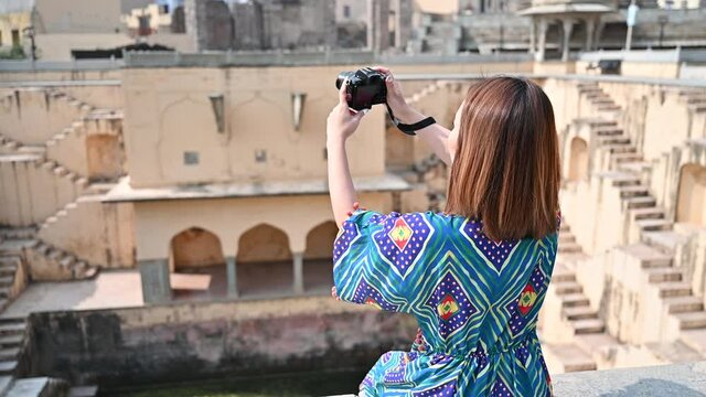 Asian woman traveling and photographing stepwell in Rajasthan