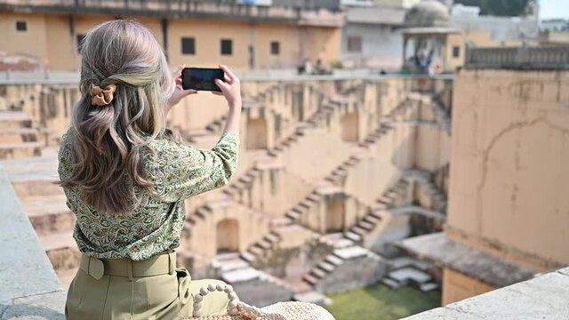 Asian woman traveling and photographing stepwell in Rajasthan