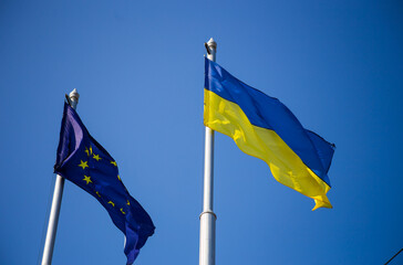 European union flag and ukrainian flag fluttering against blue sky background