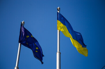 European union flag and ukrainian flag fluttering against blue sky background
