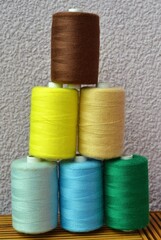 Tower of colored threads on a light purple background