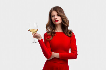 Woman with makeup, hairstyle waering red dress posing with glass of vine over white background, isolate.