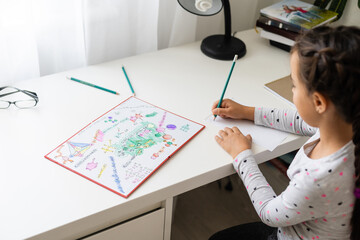 cute happy little girl writing something in her notebook