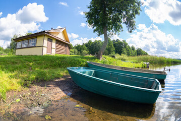 Two plastic fishing boats and wooden bath at the bank of the lake