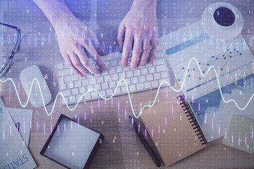 Multi exposure of man's hands typing over computer keyboard and forex graph hologram drawing. Top view. Financial markets concept.