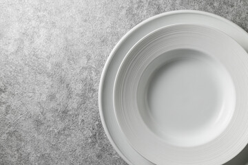 two modern white plates on a concrete background, top view