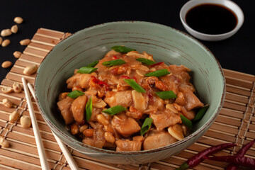 Kung Bao chicken on a black background. A Chinese dish with chicken, chili, peanuts, sauces and onions.