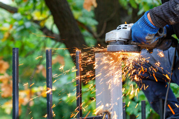 Bright, hot sparks fly out from under the protective cover of the angle grinder when cutting metal.