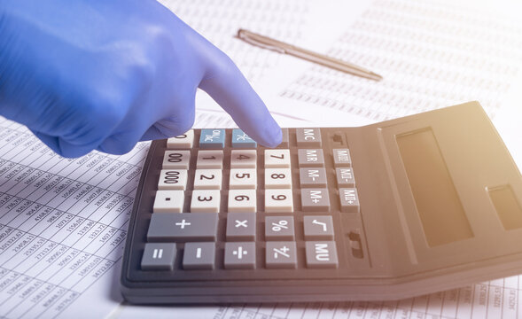 financial analysis concept during pandemic, male hands using a calculator in protective gloves, extra closeup