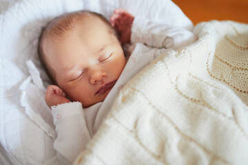 Newborn baby sleeping under knitted blanket