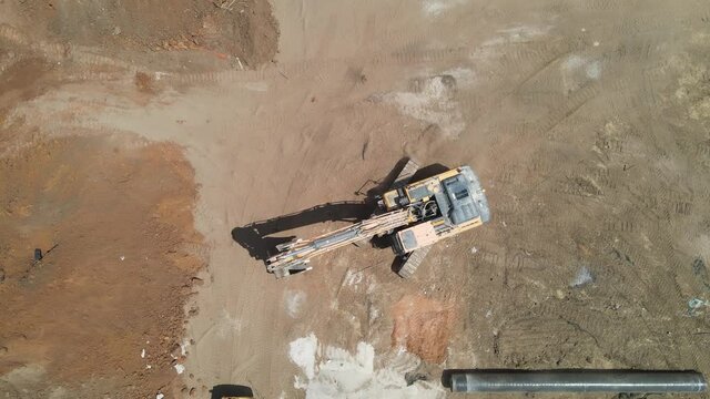 Aerial view of heavy machinery, excavator work on construction site, heavy equipment top down footage
