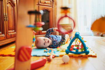 Naklejka premium Baby girl playing with toys on the floor