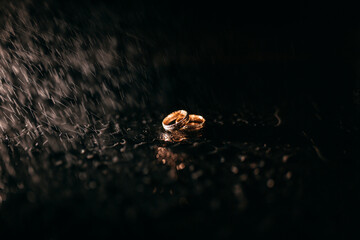 Trauringe im Dunkeln mit Wassertropfen