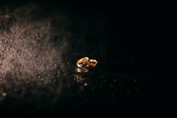 Trauringe im Dunkeln mit Wassertropfen