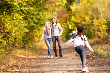 Obraz premium Happy family having fun outdoors in autumn park against blurred leaves background