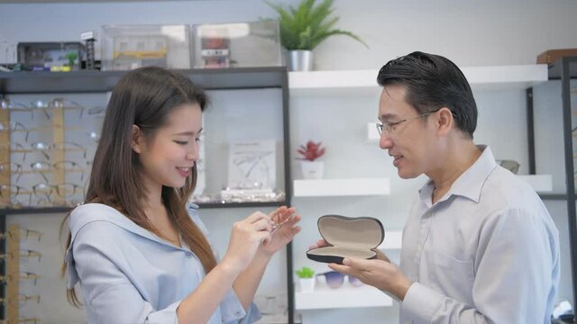 Optical shop concept. The shopkeeper is introducing glasses to customers. 4k Resolution.