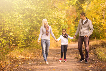 Happy family having fun outdoors in autumn park against blurred leaves background